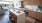 Spacious and well lit kitchen with wood floors and stainless steel appliances. 